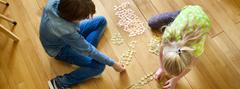 Children sit on the floor and count money.