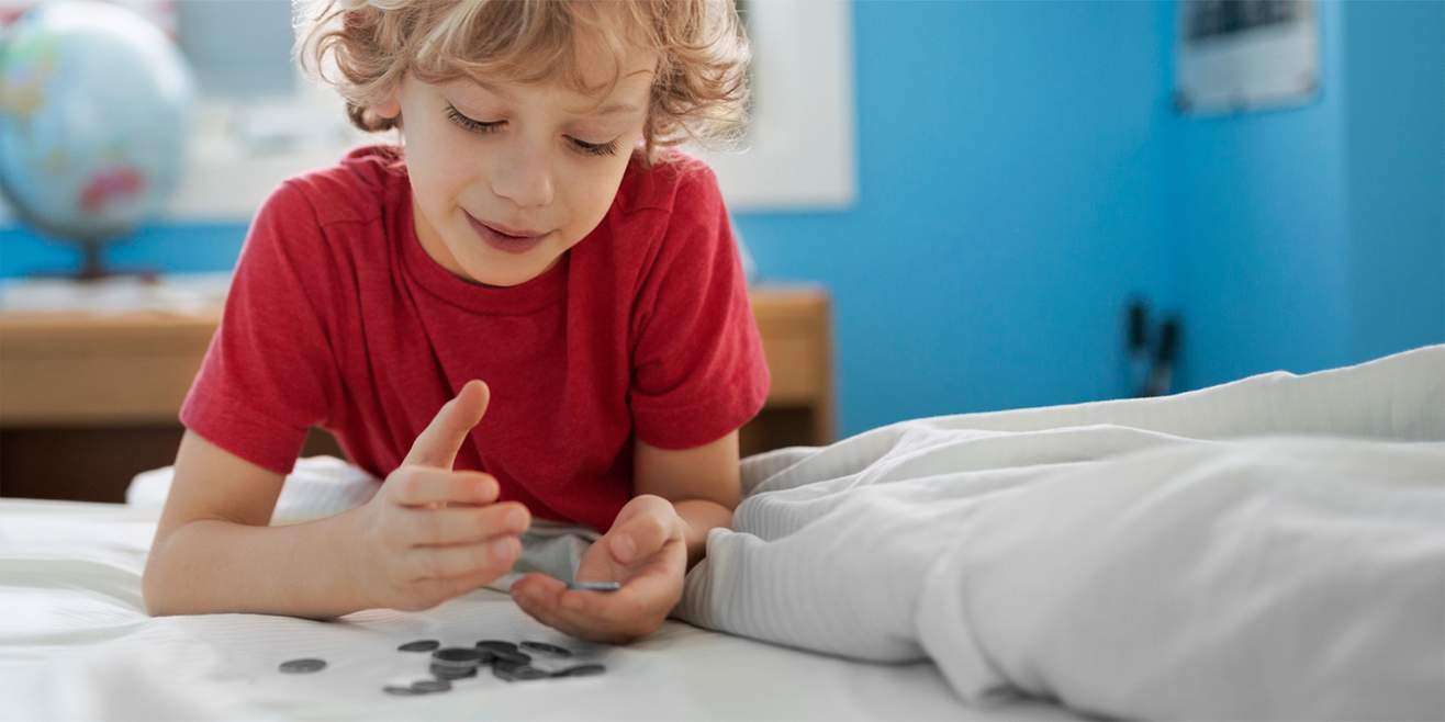 A boy is lying on his bed counting his pocket money.