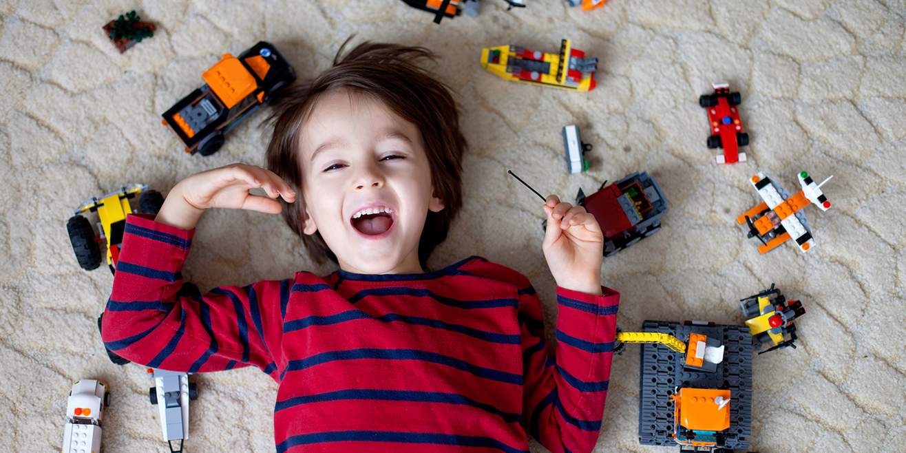 Smiling boy surrounded by toys on the floor